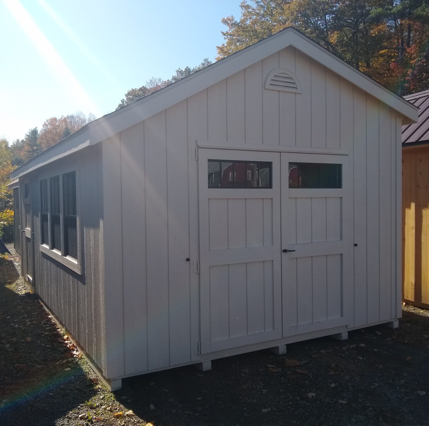 Cream colored shed with double doors and 3 windows