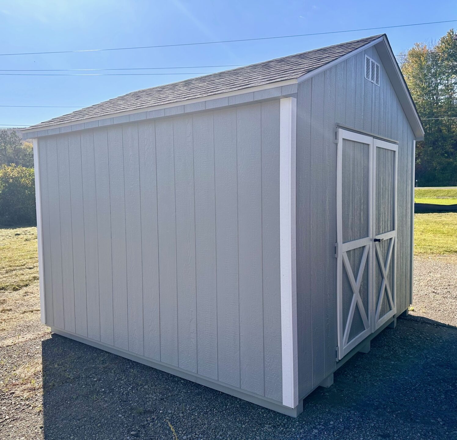 Light gray shed with white trim double doors and one window