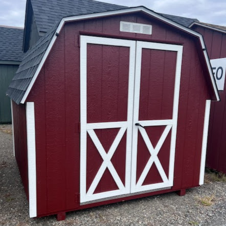 Small red barn with white trim double doors and shingles