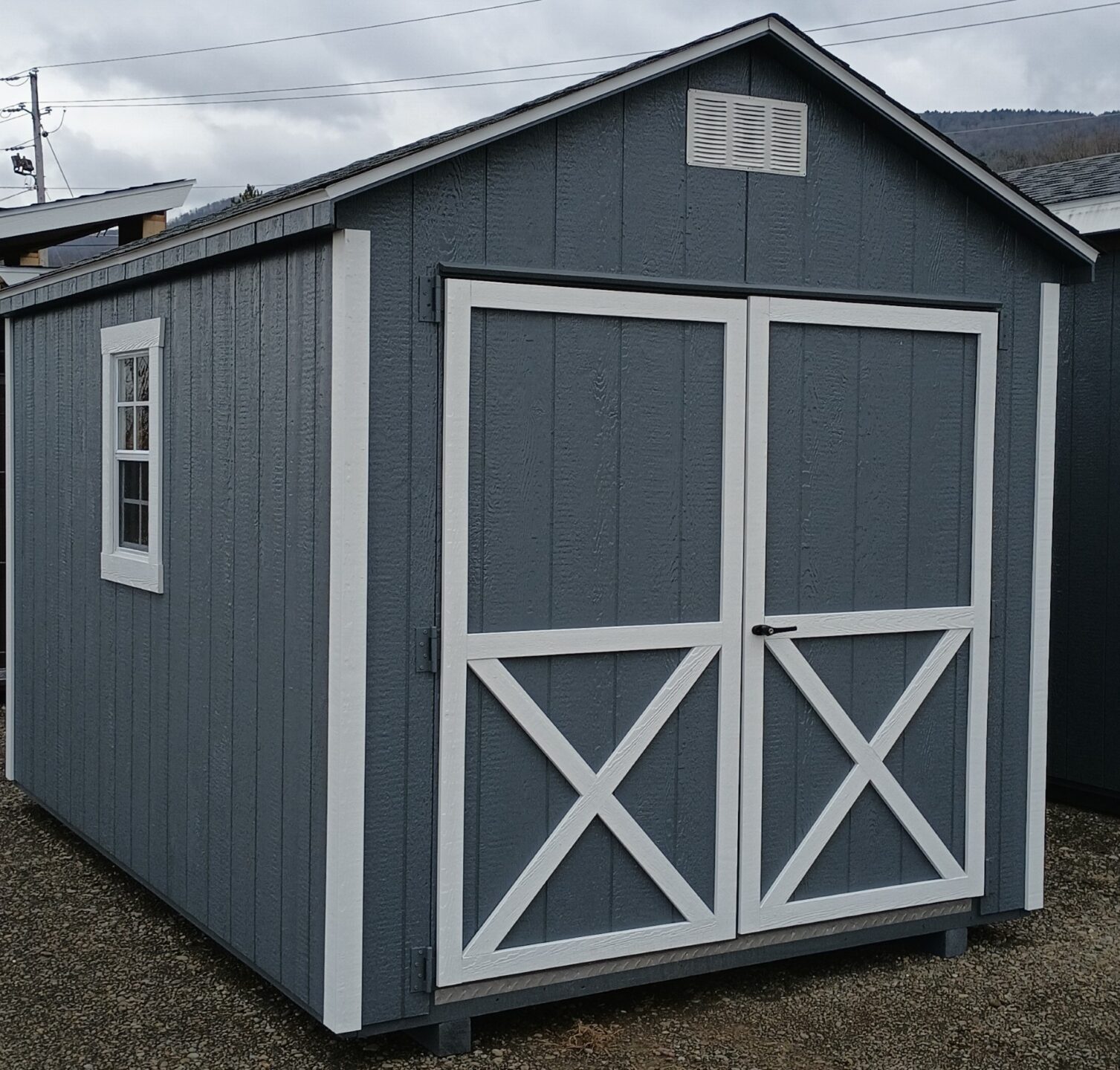 Dark gray shed with white trim double doors and 2 windows