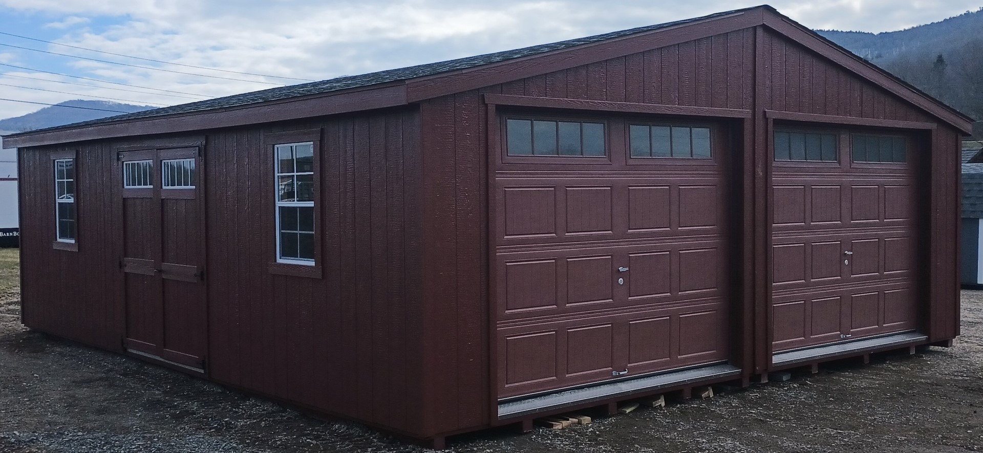 Double garage with red garage doors, windows and a 6' double door on the side