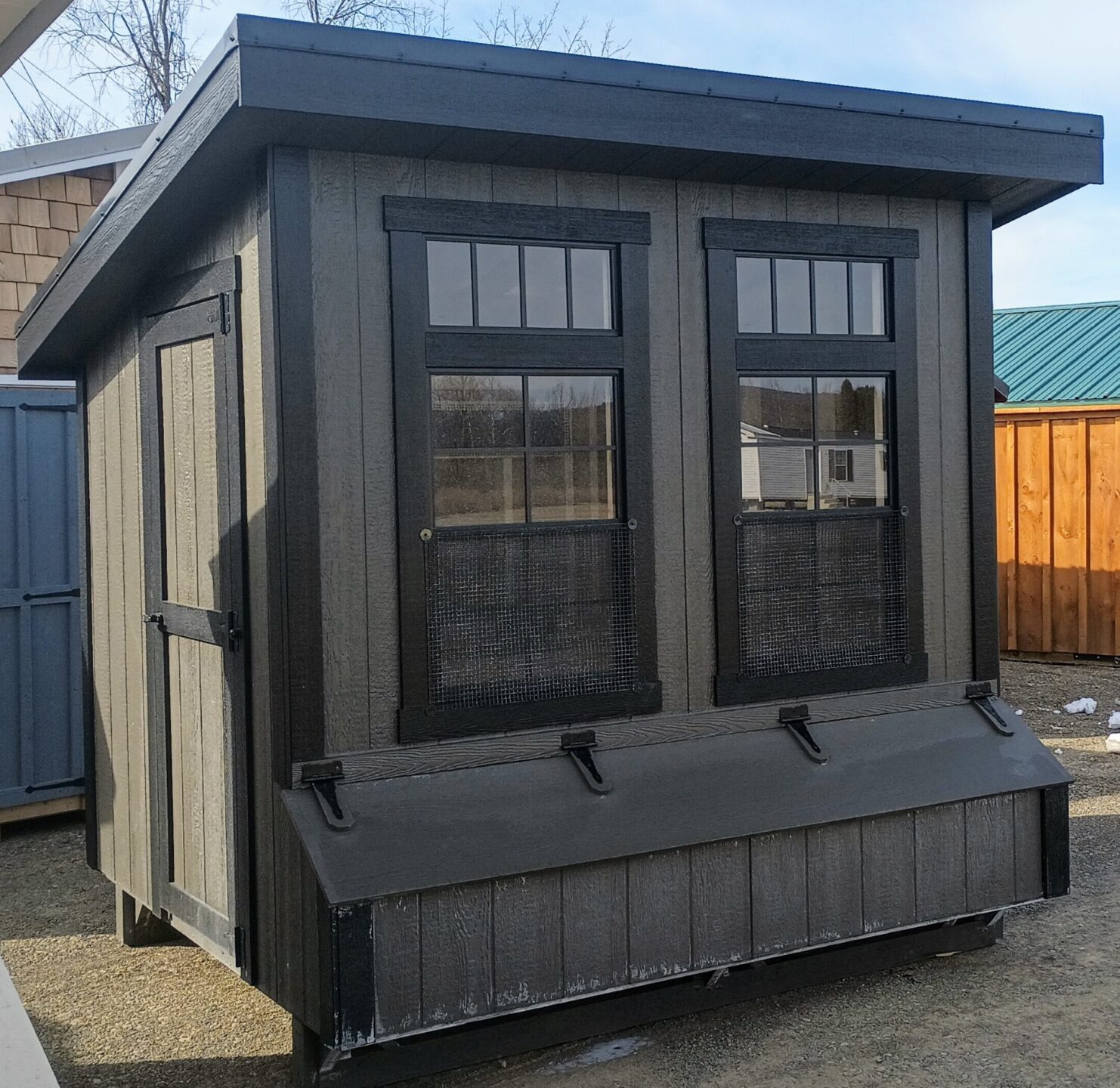 One slant chicken coop with two large windows and nesting boxes on front with a door on the side