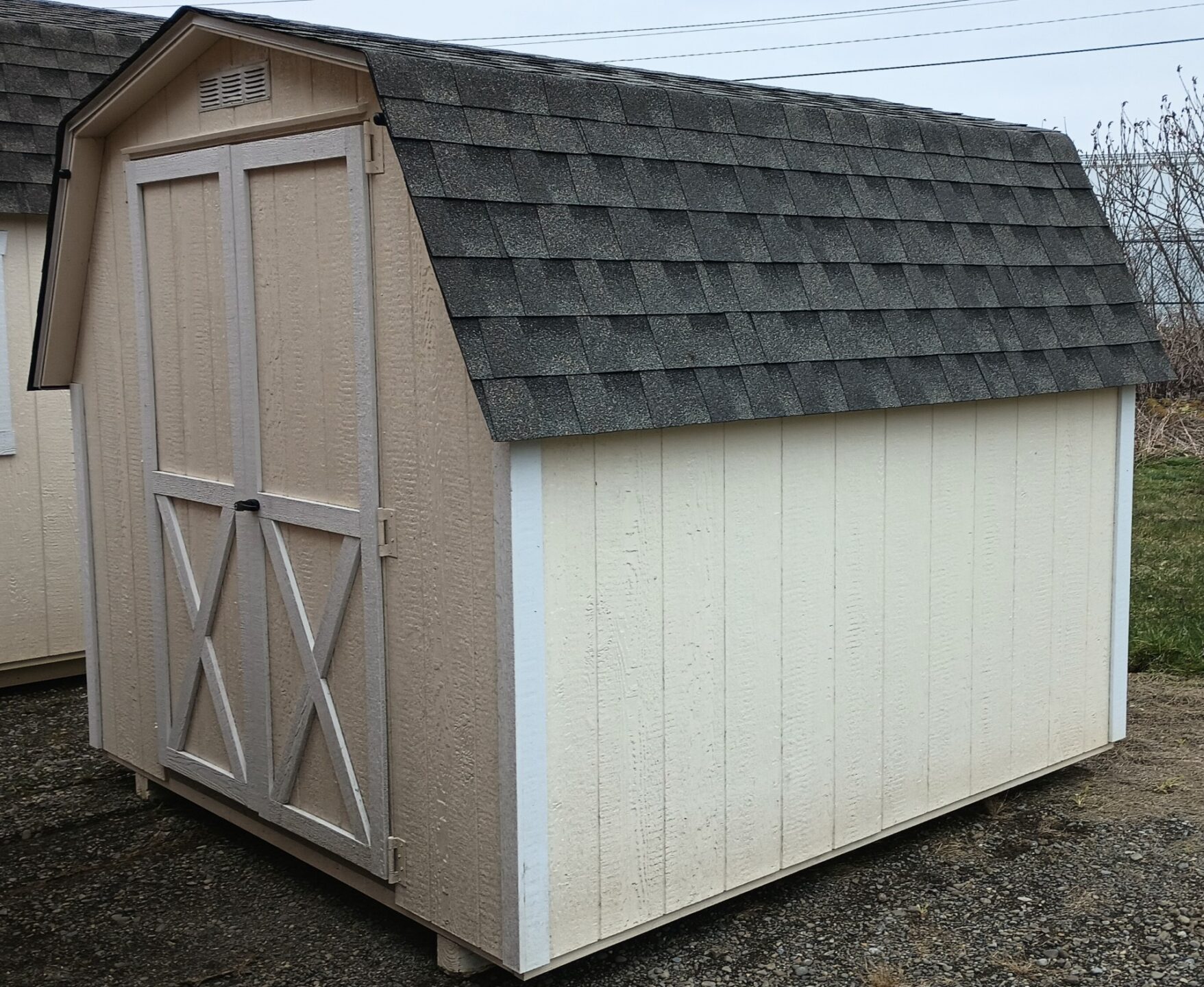 Small shed with barn style roof, double doors, shingle roof and single window on back wall
