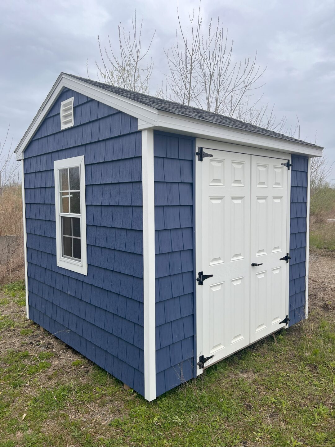 Small blue shed with white doors and windows