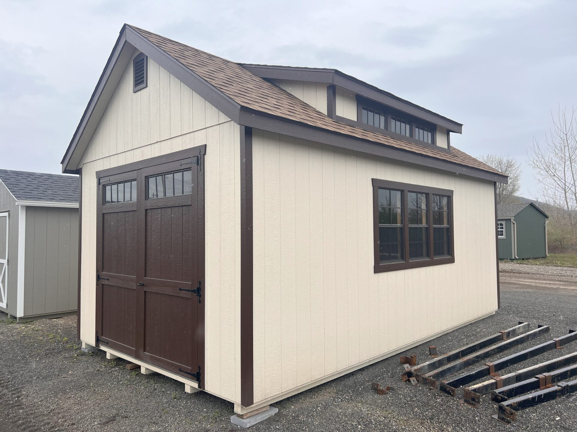 Cream color shed with double door with transom windows and transom dormer on roof