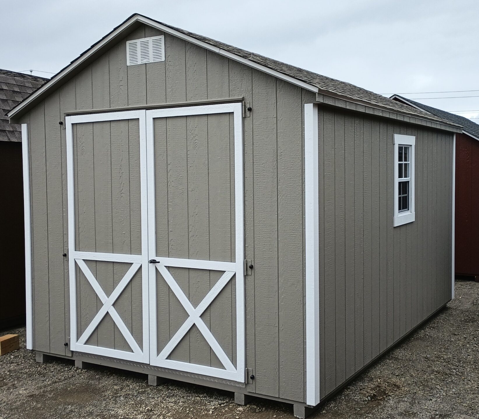 A frame shed painted clay with white trim, double doors and windows