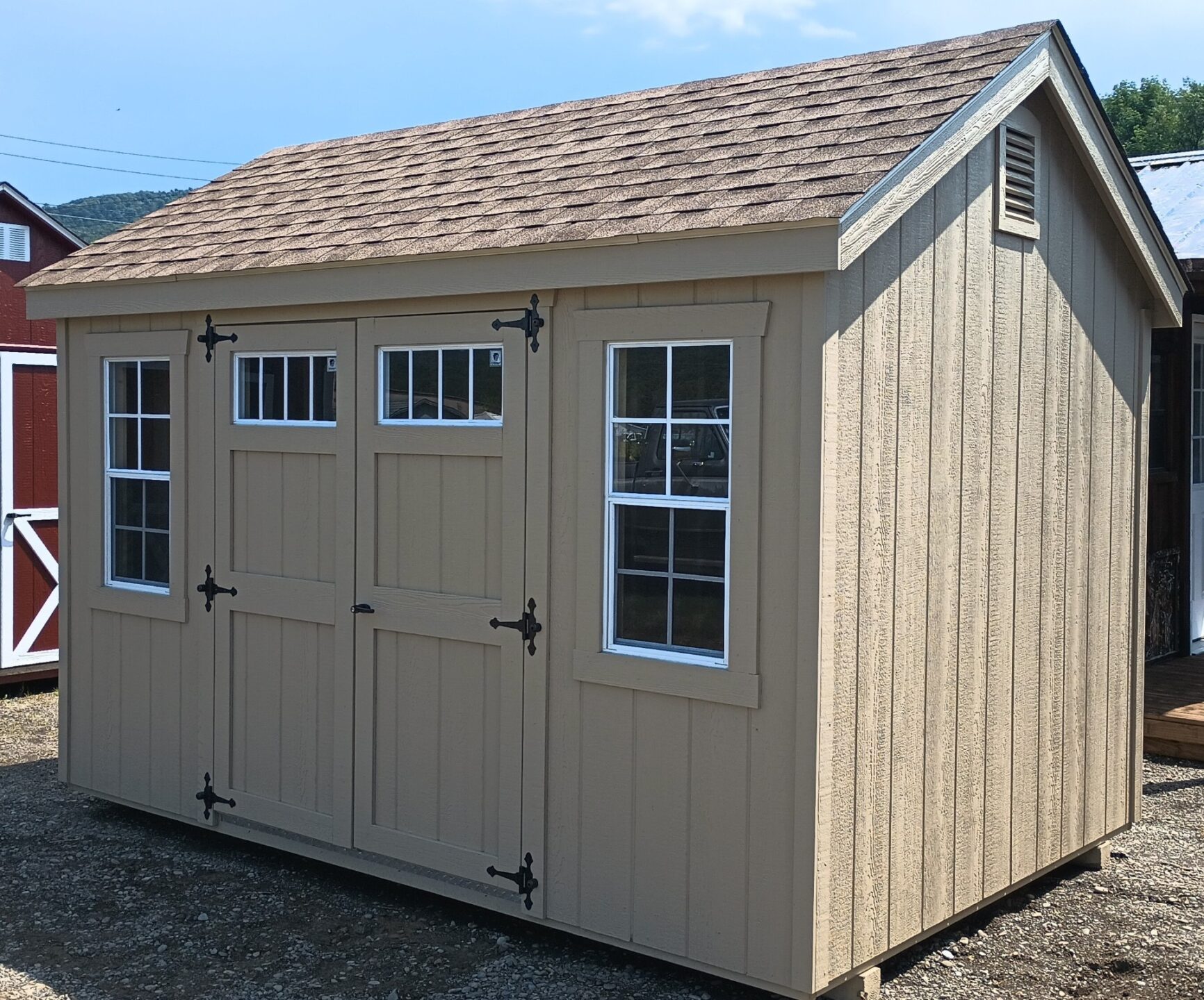 Small tan shed with double doors, 2 windows and shingled roof