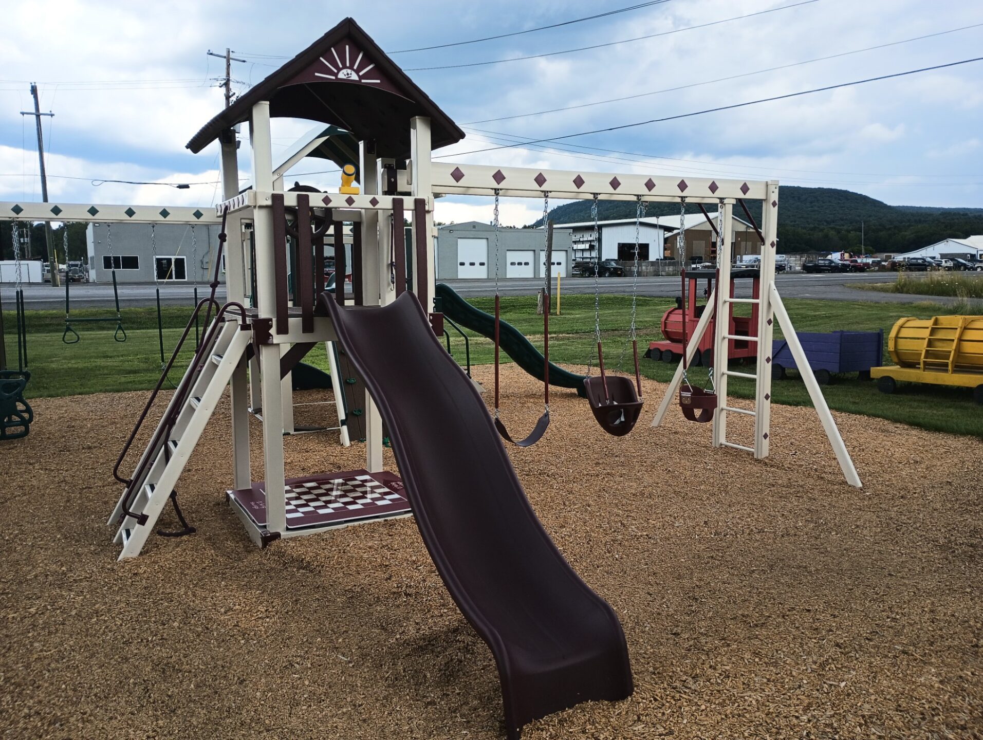 Swing set with slide and swings, as well as a small rock wall and sandbox