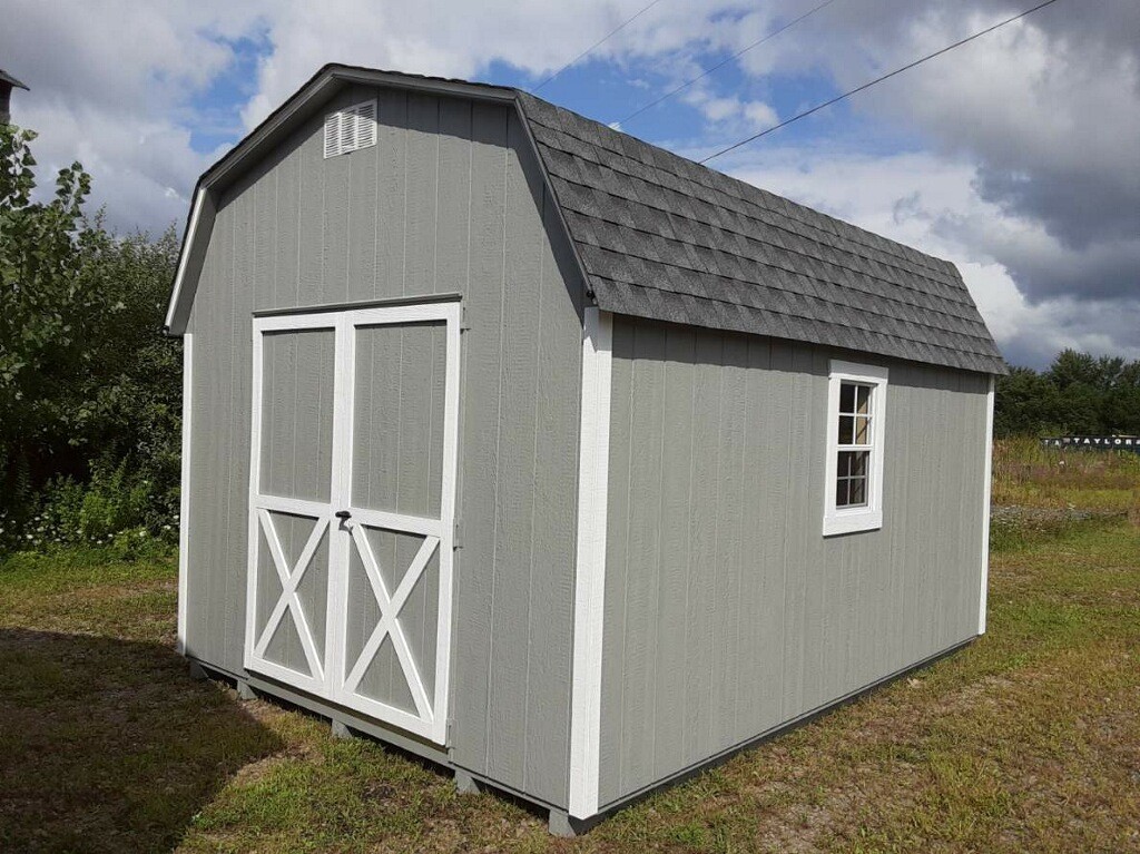 Gray barn with white trim, shingles, double doors and two windows