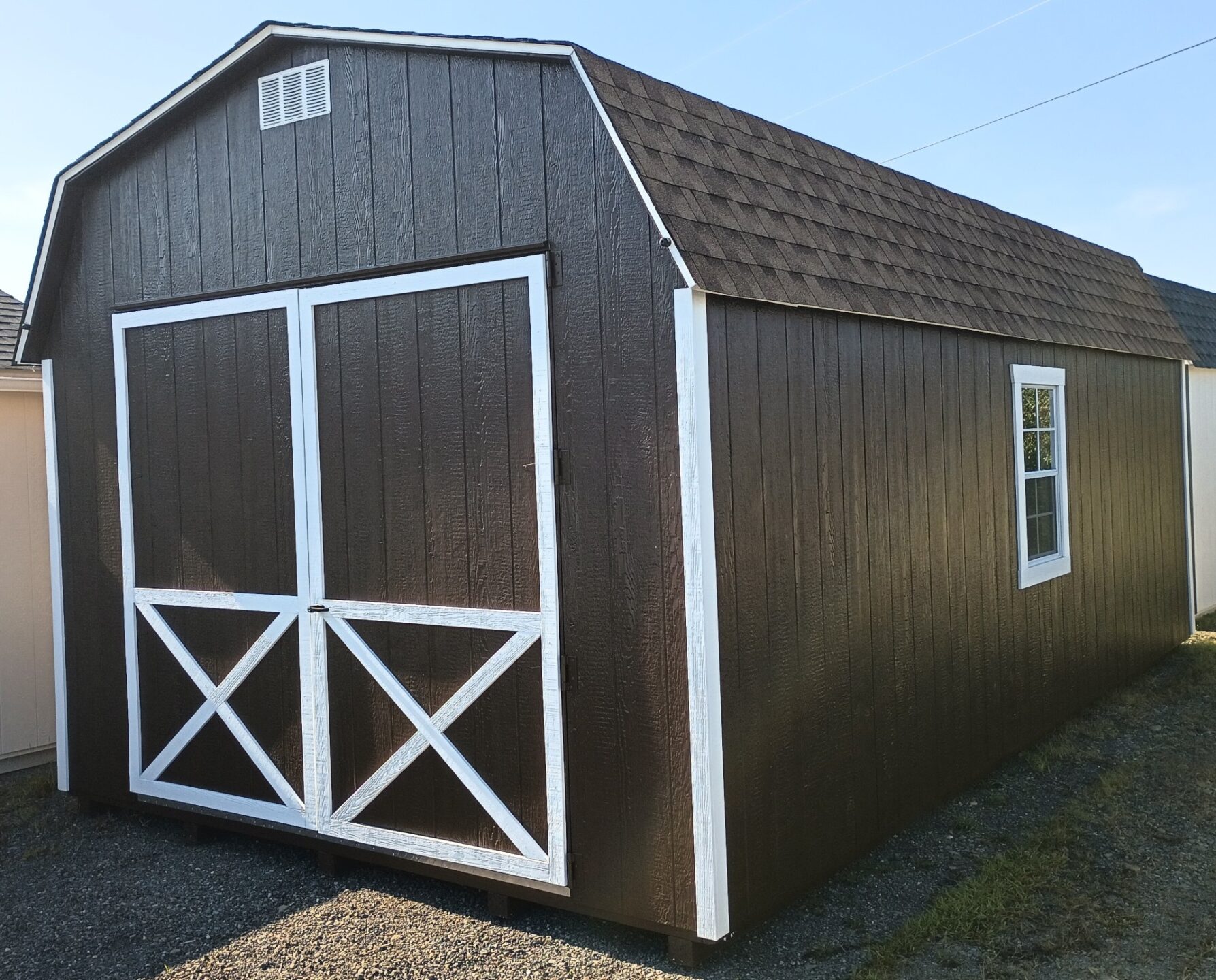 Large brown shed with oversized doors, windows and shingled roof