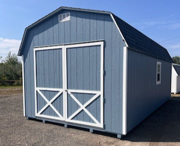 Large blue shed with white trim, oversized double doors, and windows on each side