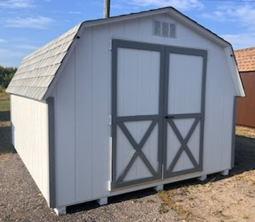 Small white shed with gray trim, shingled roof and double doors