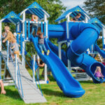 Kids and dad having fun and playing on The Rocket Launcher, a customized, vinyl-surface playset