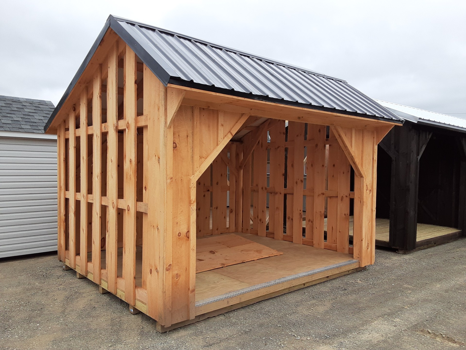 Slat sided firewood shed with metal roof and pressure treated flooring