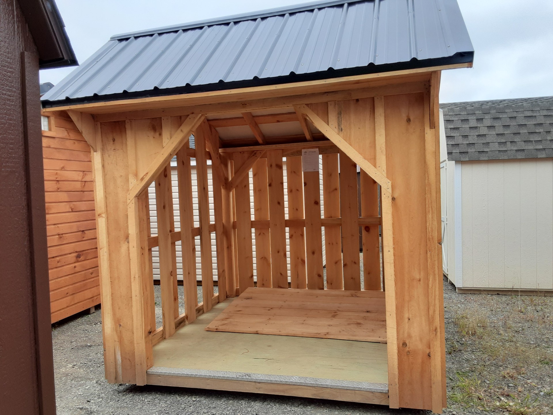 Small firewood shed with slat walls, metal roof and pressure treated flooring