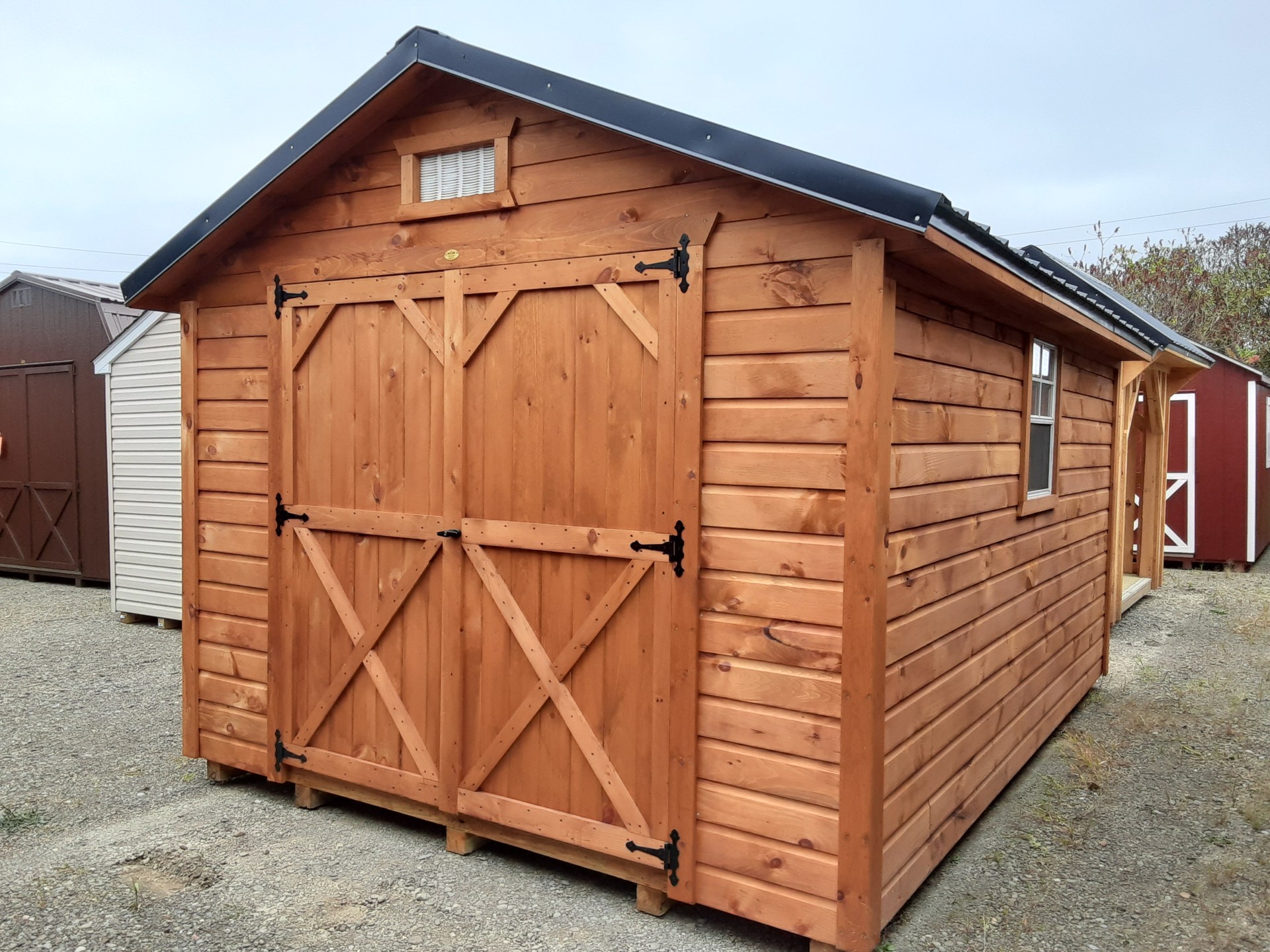 Lap sided shed with double doors and a metal roof with window on either side