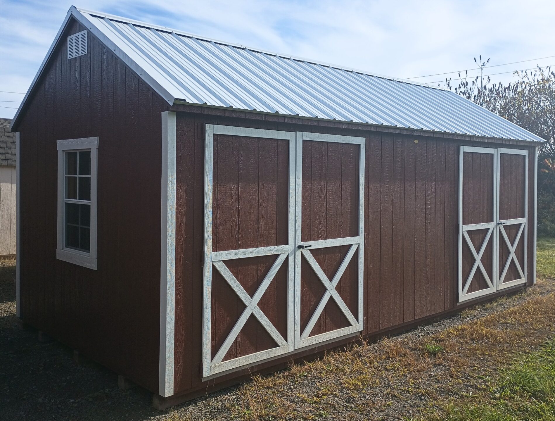 Large red shed with two sets of double doors and windows on either end