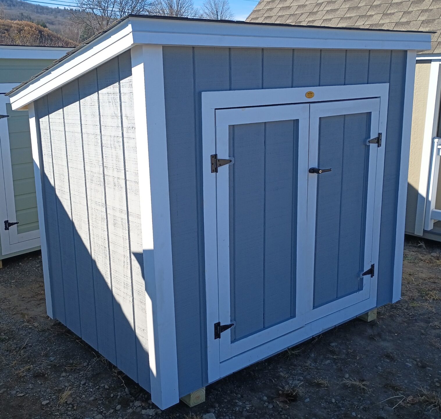 Small gray shed with double doors and one slant roof