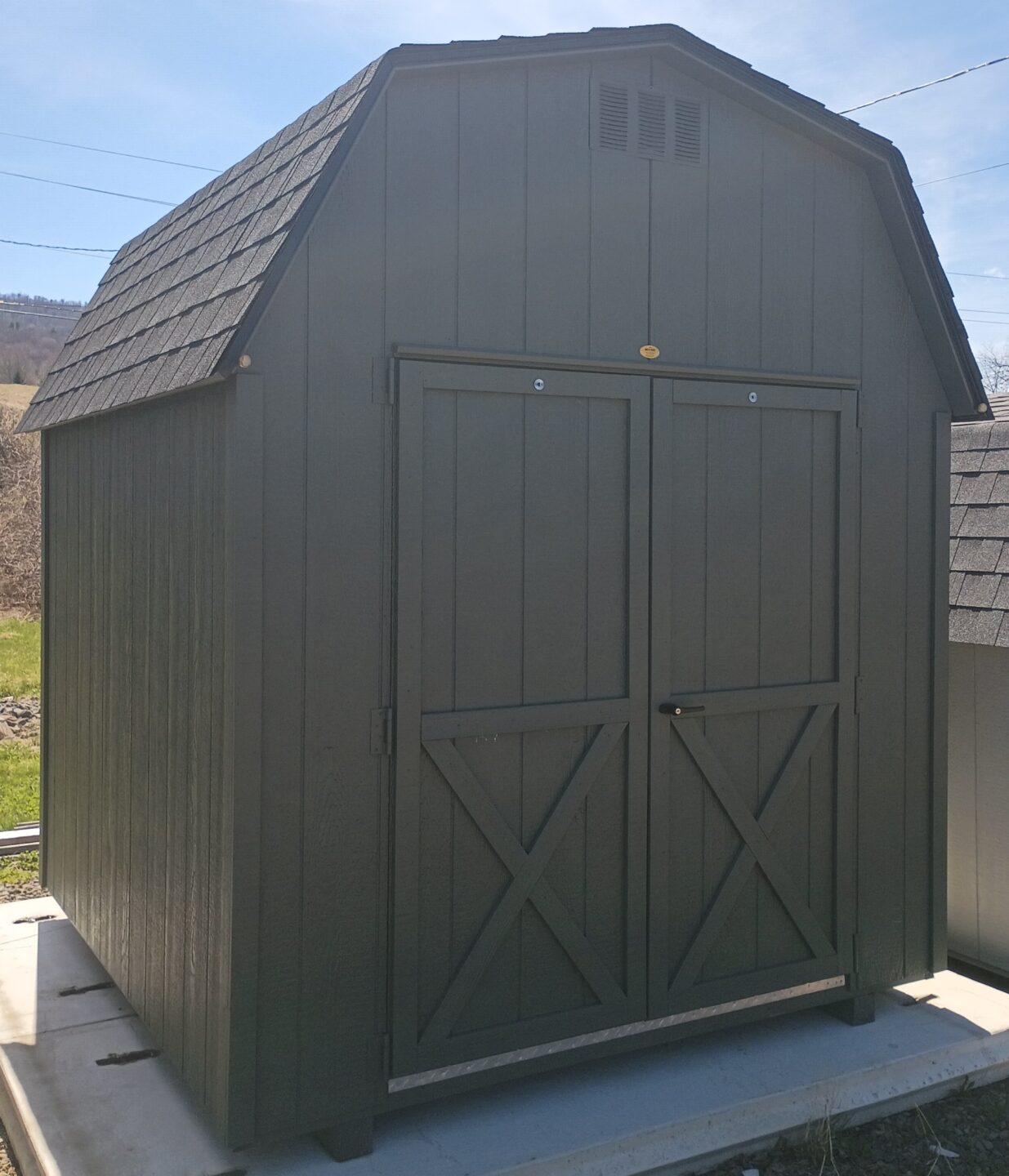 Small shed with barn roof and double doors with shingles on the roof