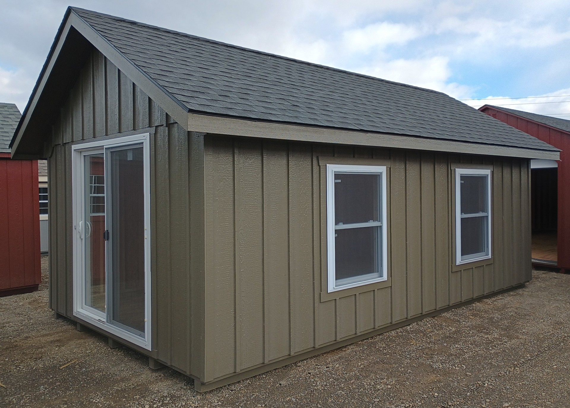 Board and batten painted shed with sliding glass doors, shingled roof and large vinyl insulated windows