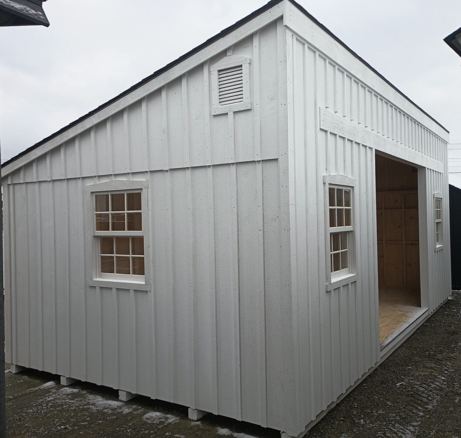 Large white board and batten shed with double doors and 4 wooden windows