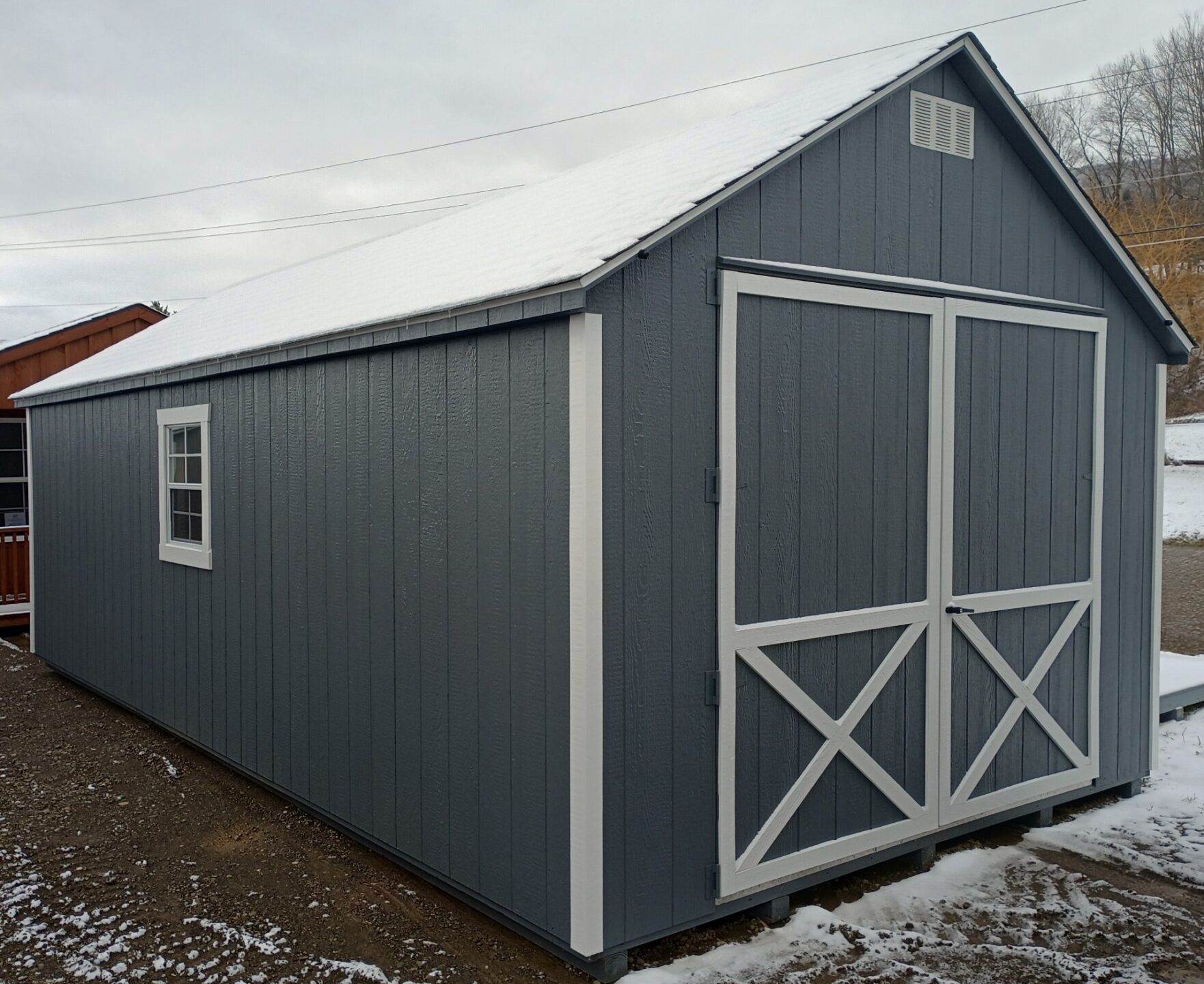 Large grey shed with white trim, double doors, shingled roof and gable vents