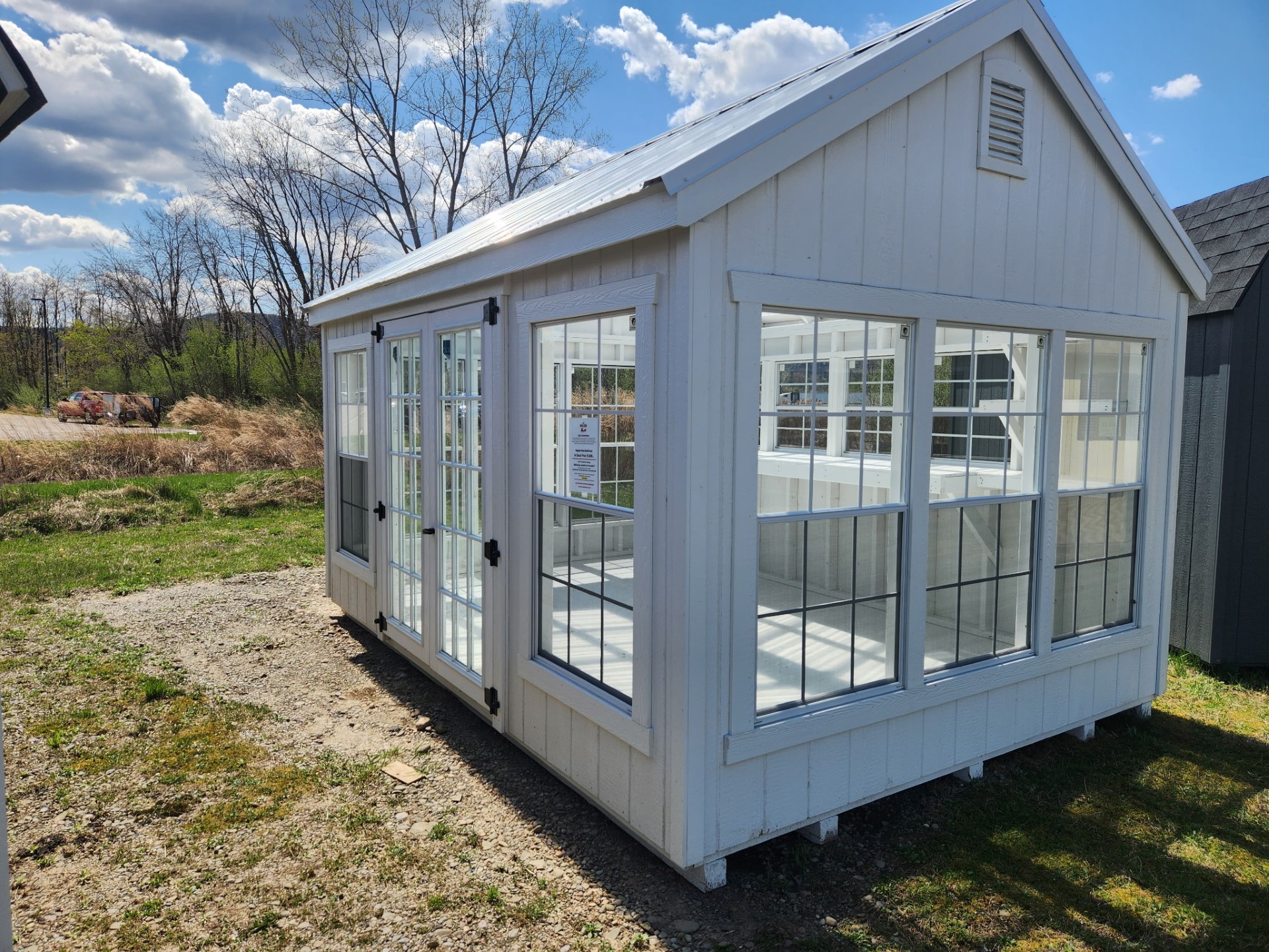 White shed with windows, clear roof and glass double doors