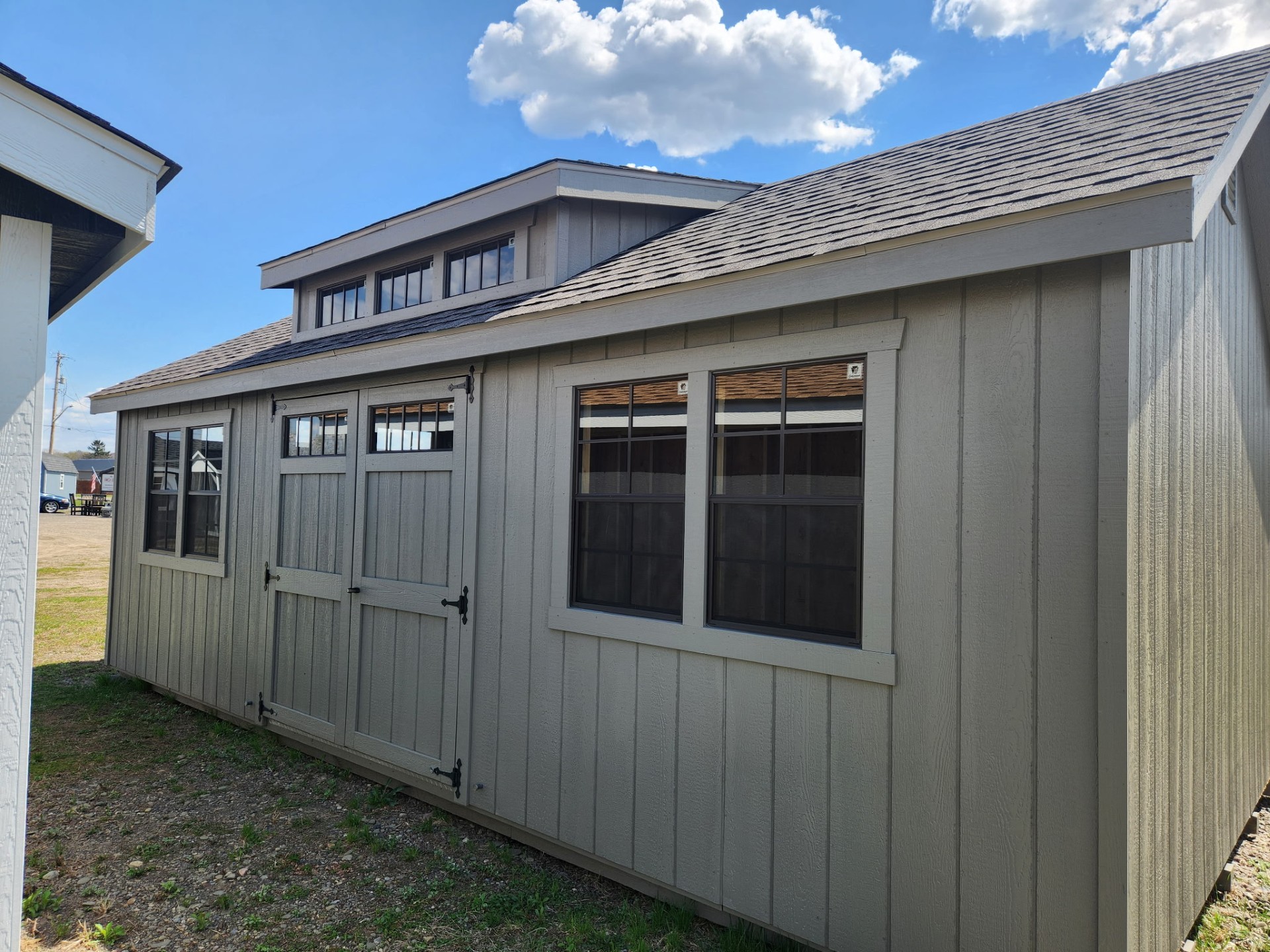 Shed with Garage door at end, double doors and windows on long side and transom dormer above