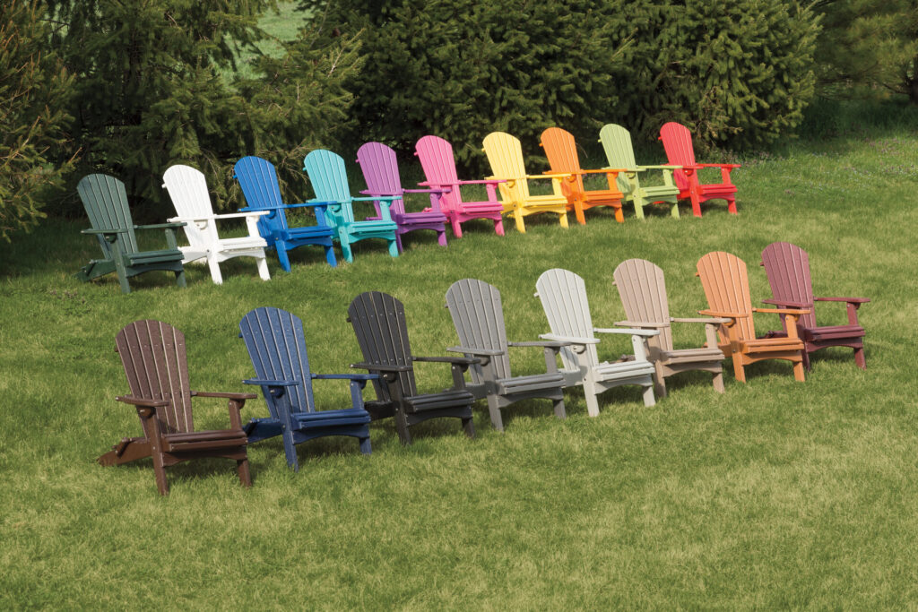 Amish-made Adirondack Chairs of a variety of colors situated on lush green grass 