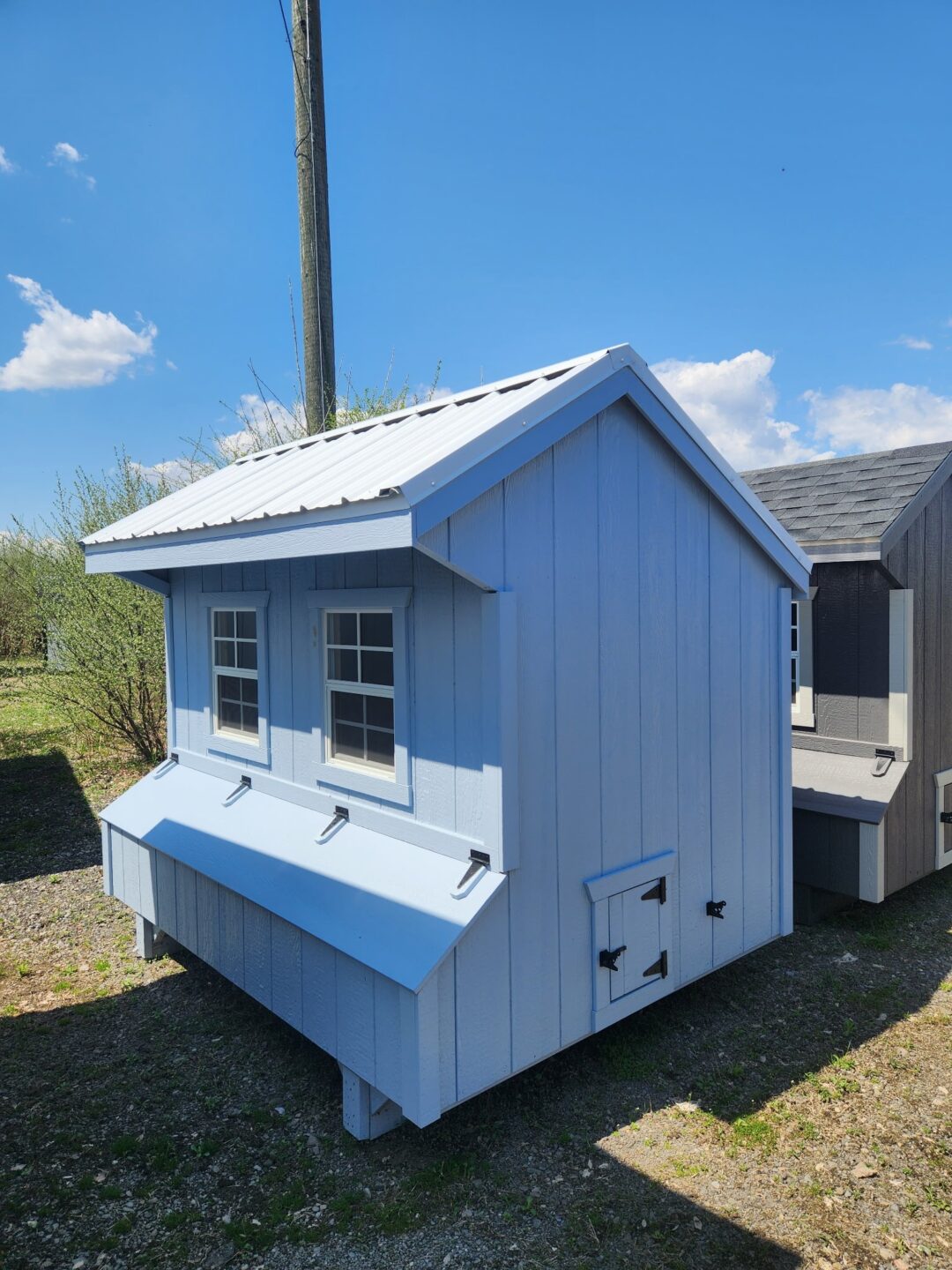 Small light blue shed with nesting boxes, door and two windows