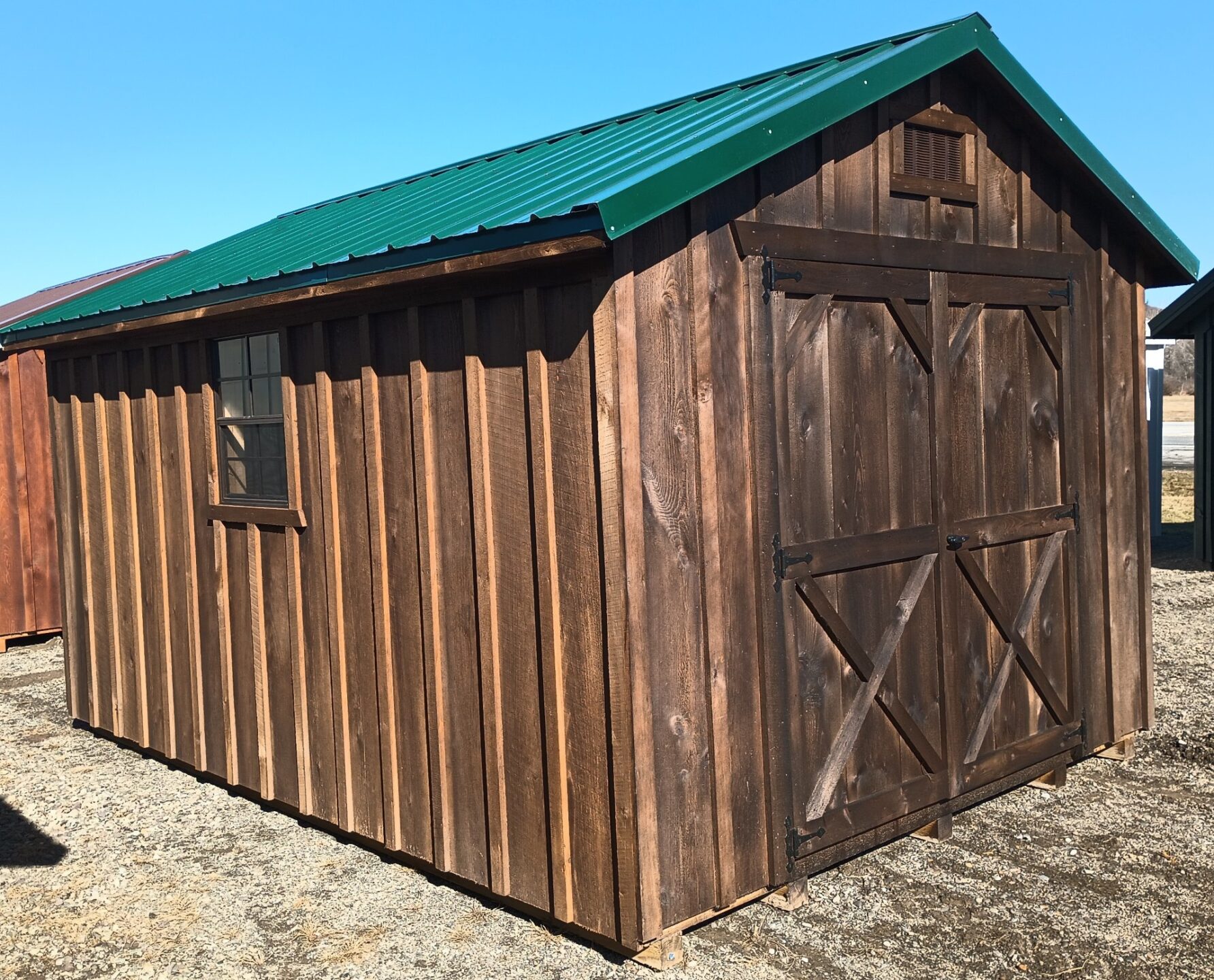 Small rustic shed with double doors, metal roof and two windows