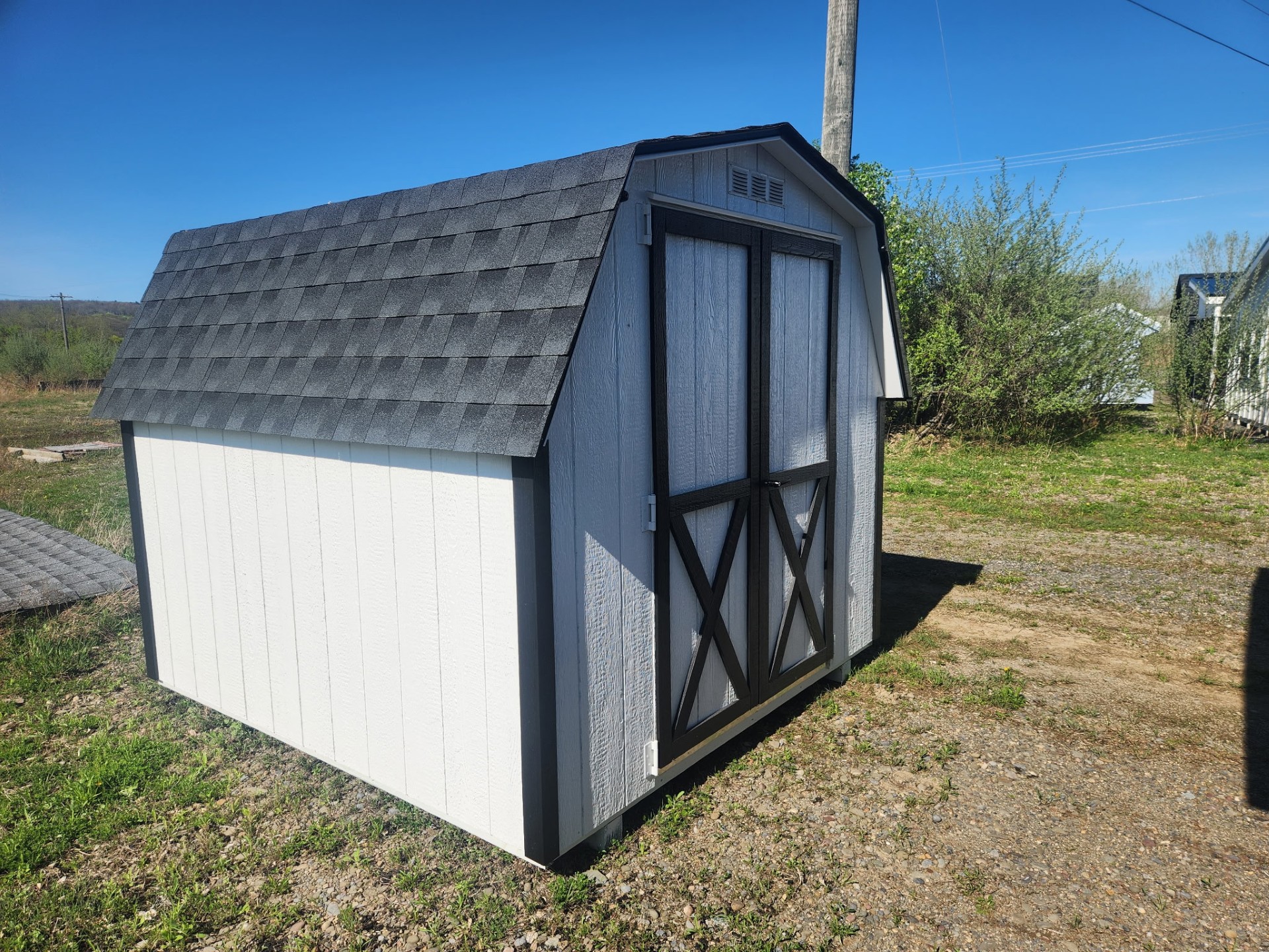 Small white wall barn with black trim and shingles