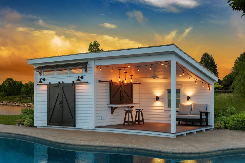 Custom-built pool house featuring bar counter and shaded seating area with a beautiful sunset backdrop