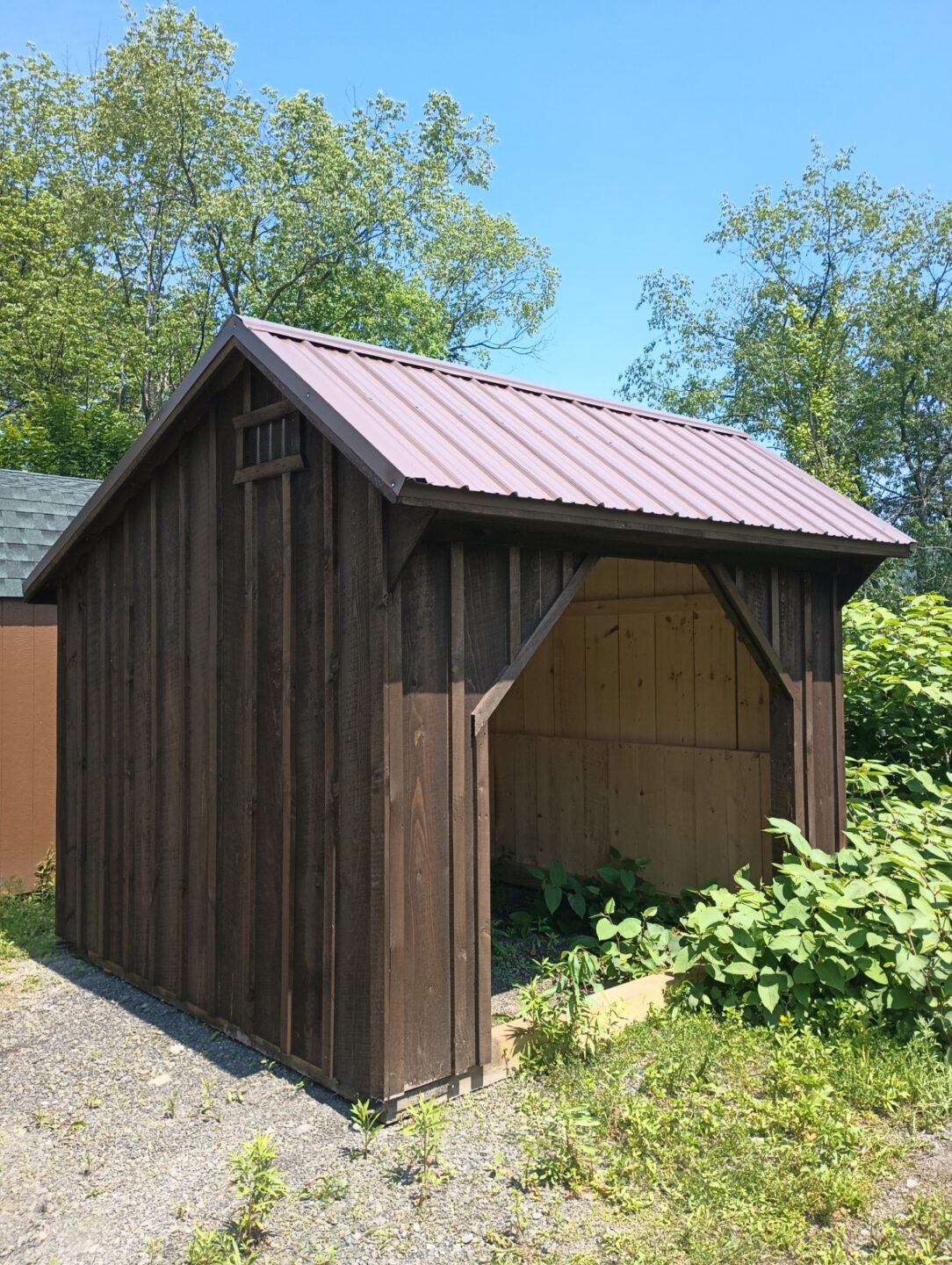 Dark color run in shed with brown roof and front opening