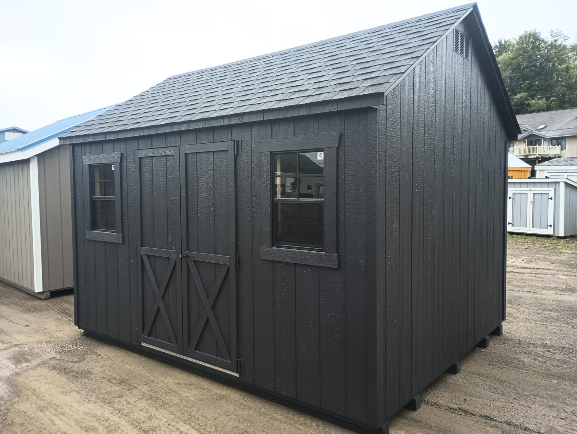 Small shed with double doors and two windows on long side with shingles on the roof