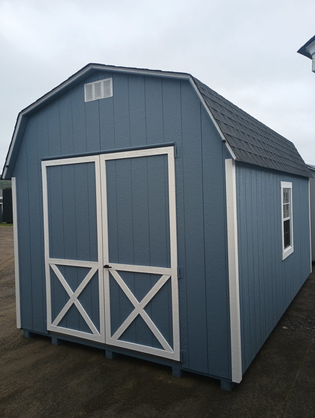Dutch barn with blue siding and white trim, architectural shingles, double doors and windows on either side