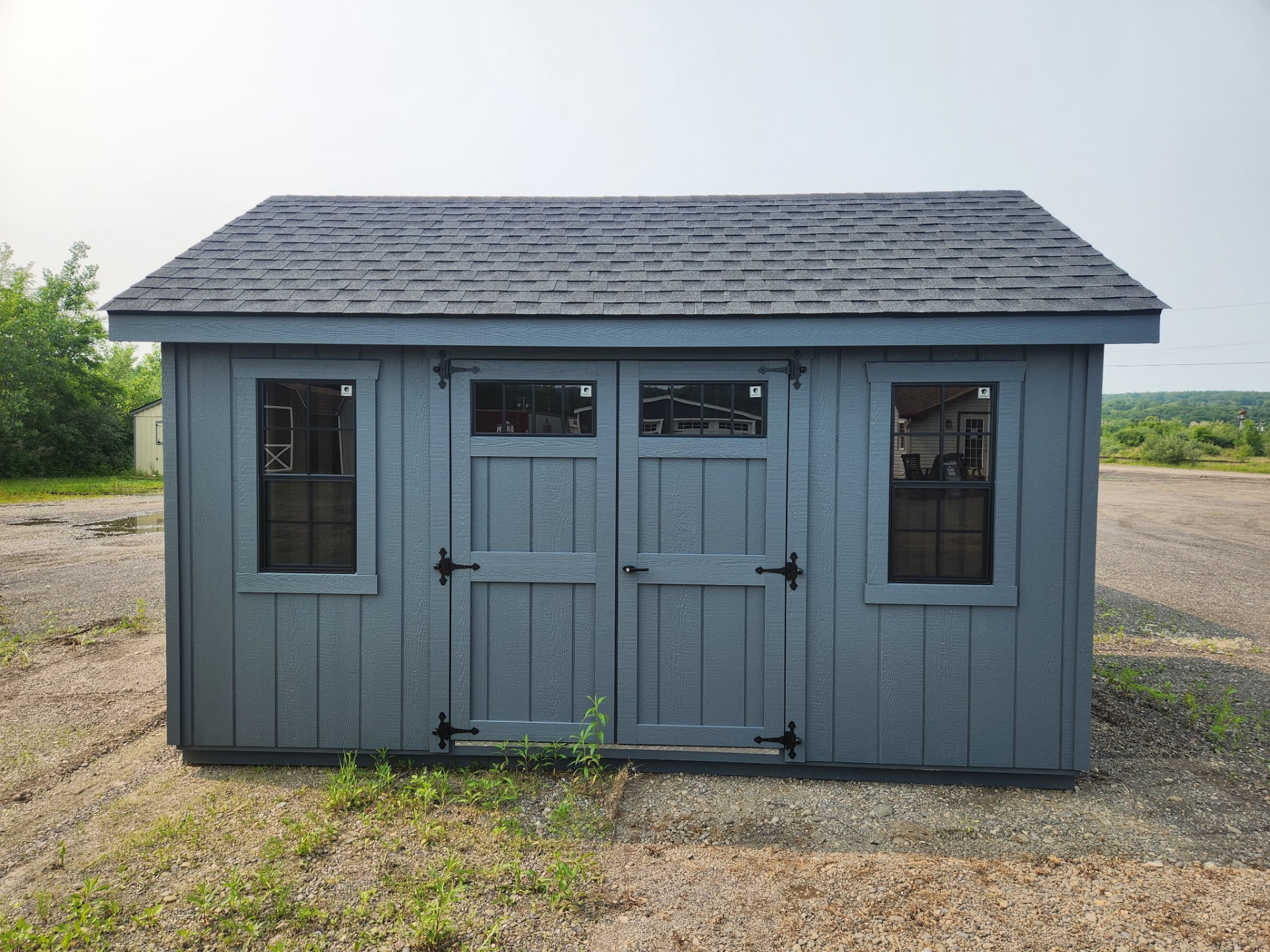 Dark gray shed with double doors and two windows on the long side.