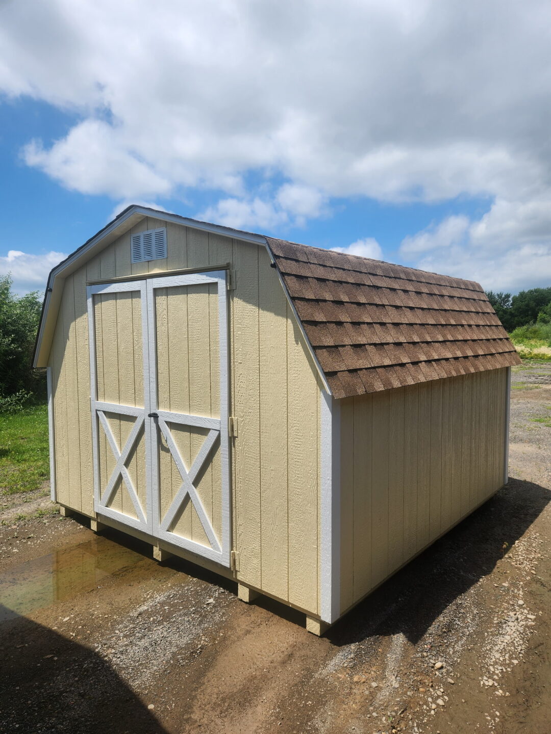 Small barn style shed with double doors, brown shingles and a window on the back wall
