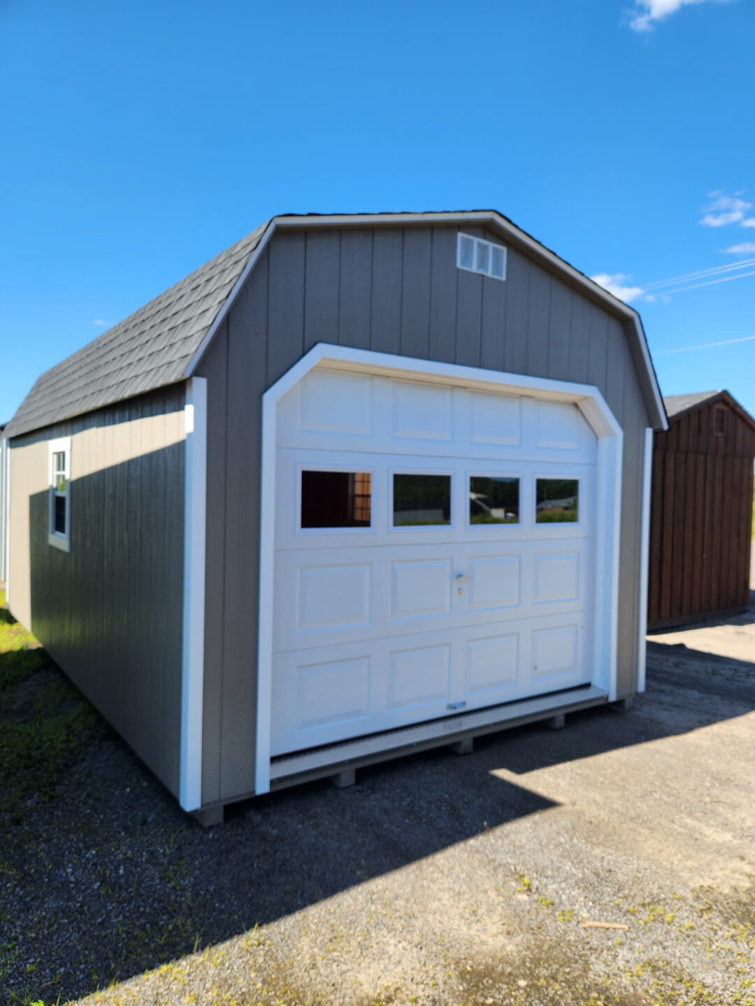 Barn style garage with overhead door, side door, shingles and two windows