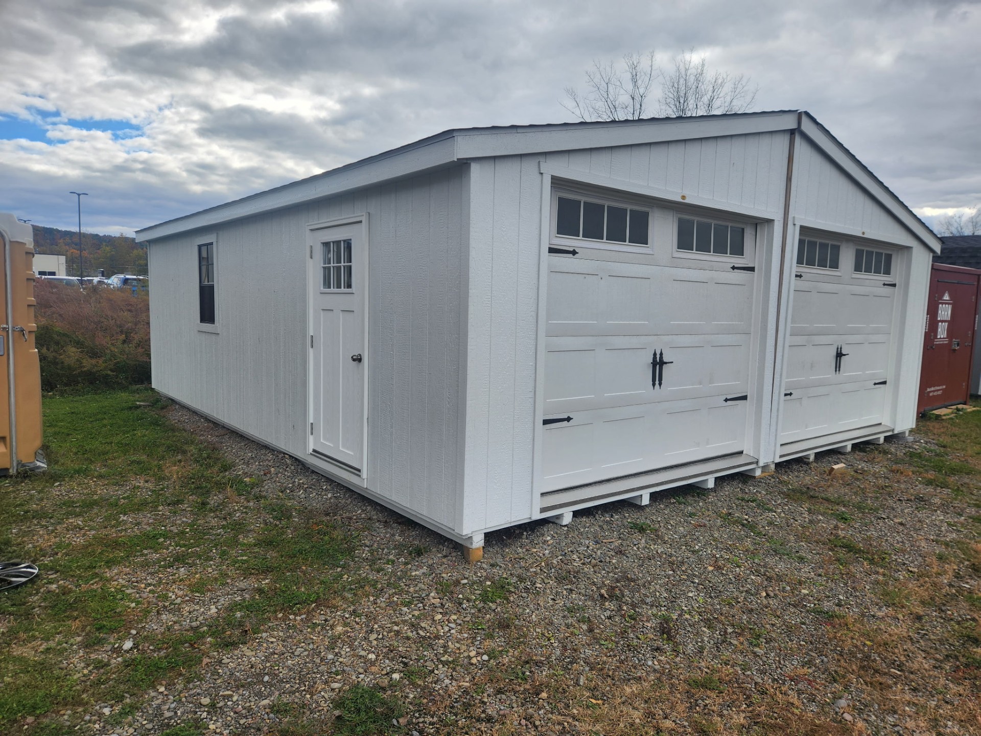 All white double garage with overhead carriage doors with windows, side door and two windows