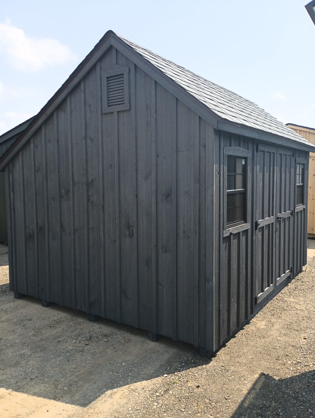 Offset roofline shed with board and batten siding, double doors and two windows on the front