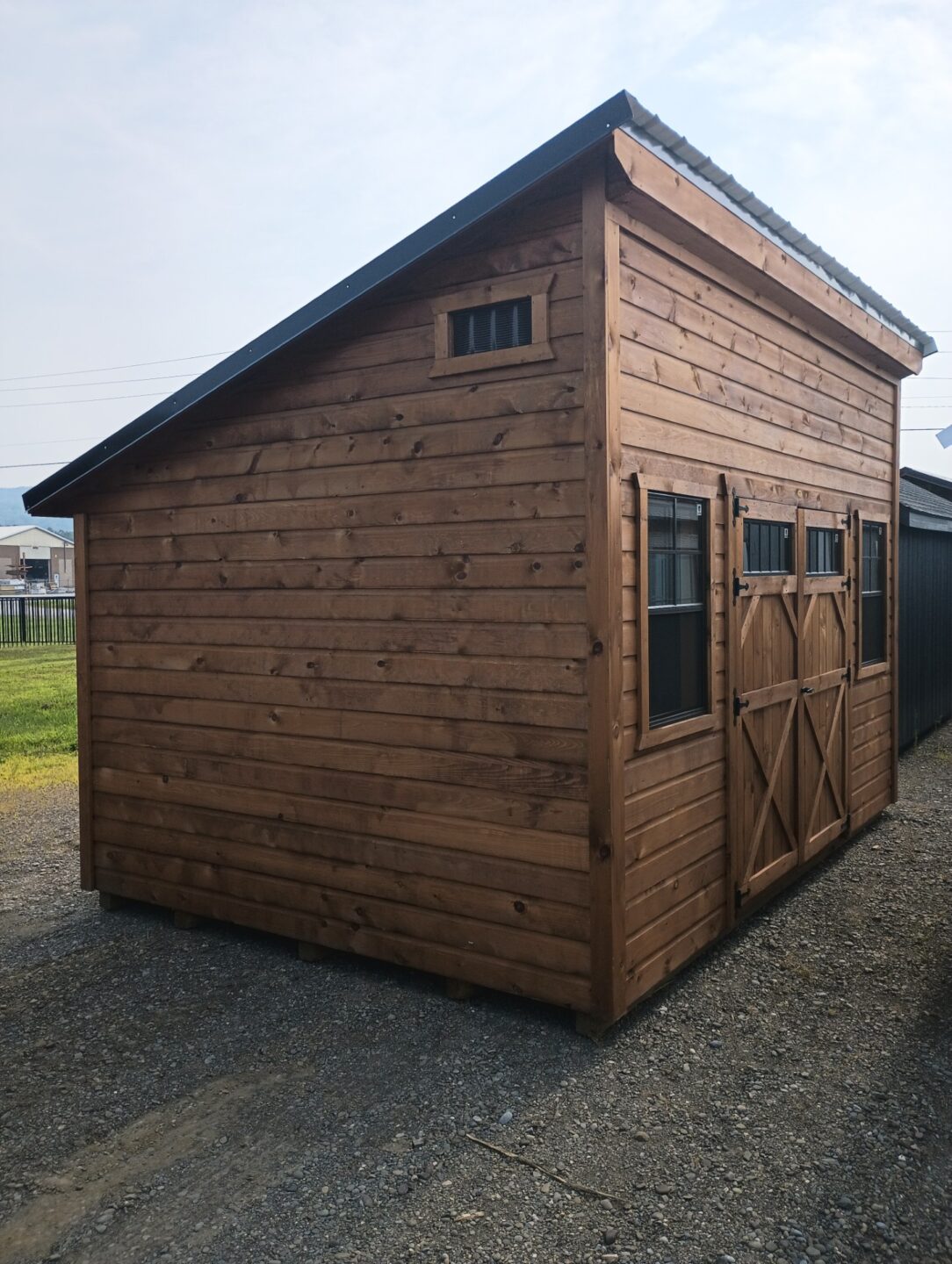 One slant shed with novelty siding, double doors and two windows on the front