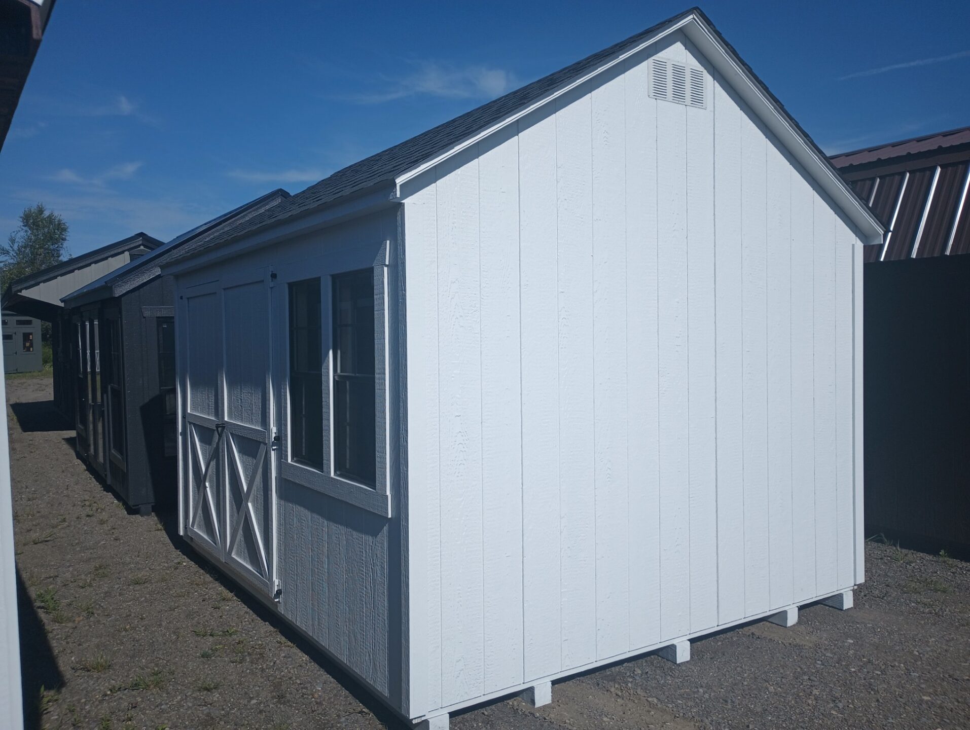 White cape cod shed with double doors and windows on long end