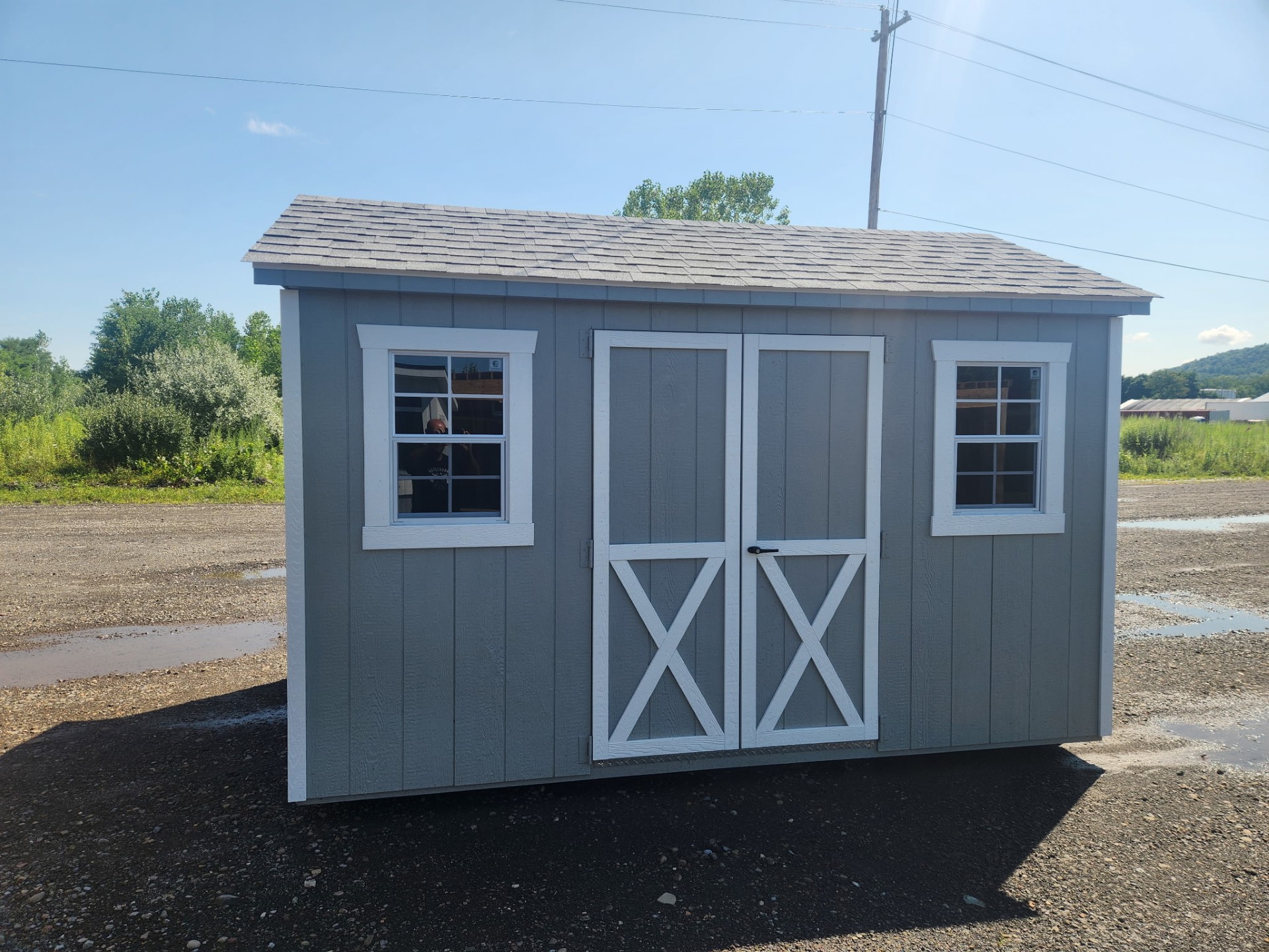 Grey a frame shed with double doors and two windows with shingled roof