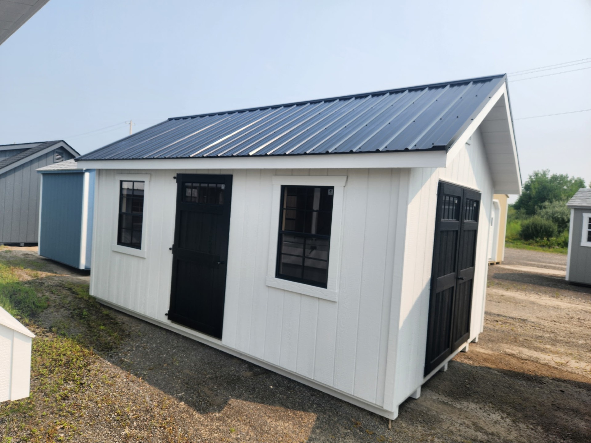 White shed with metal roof, single door, double door and four windows