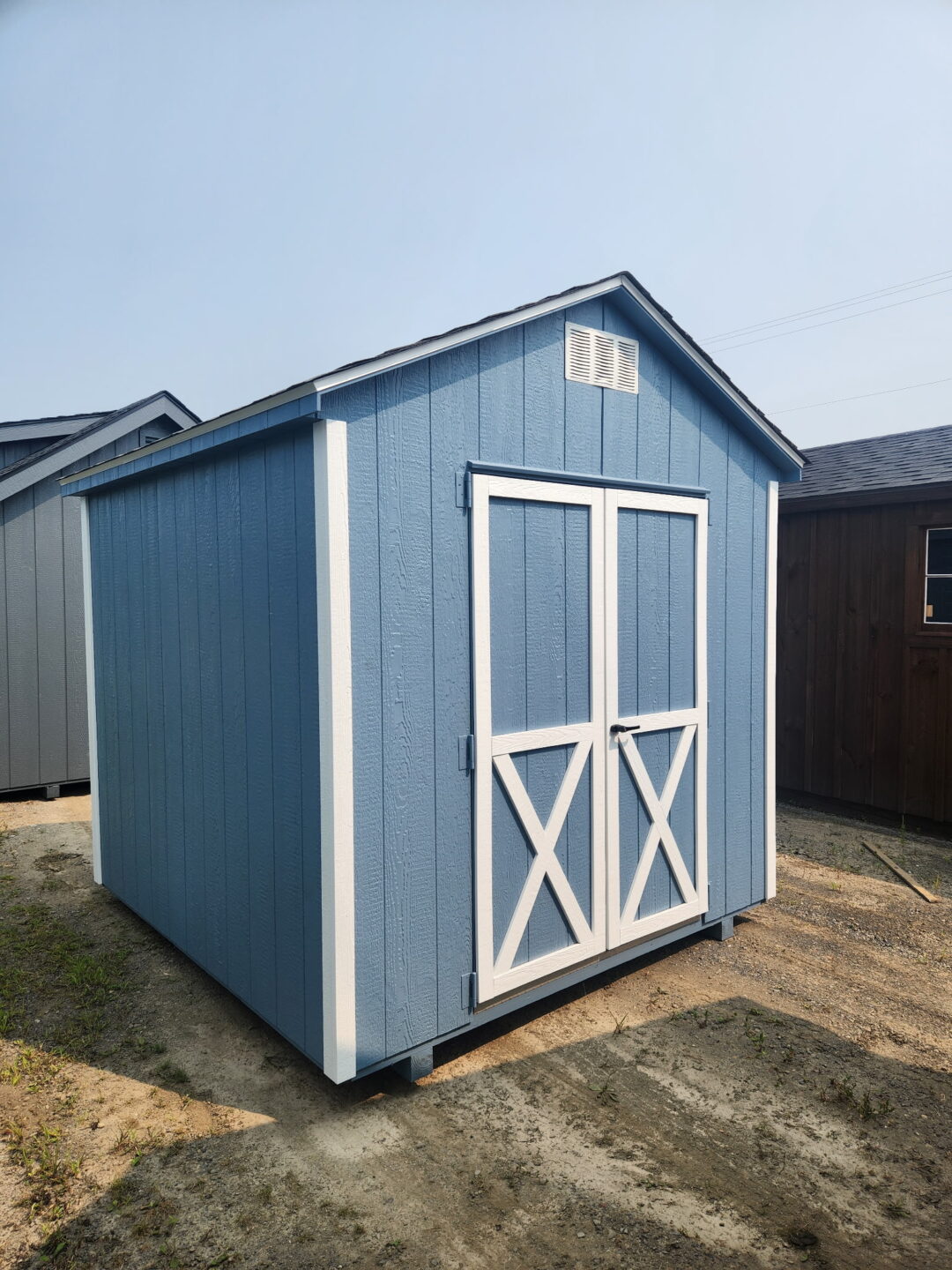 Small a frame blue shed with white trim and gable vents