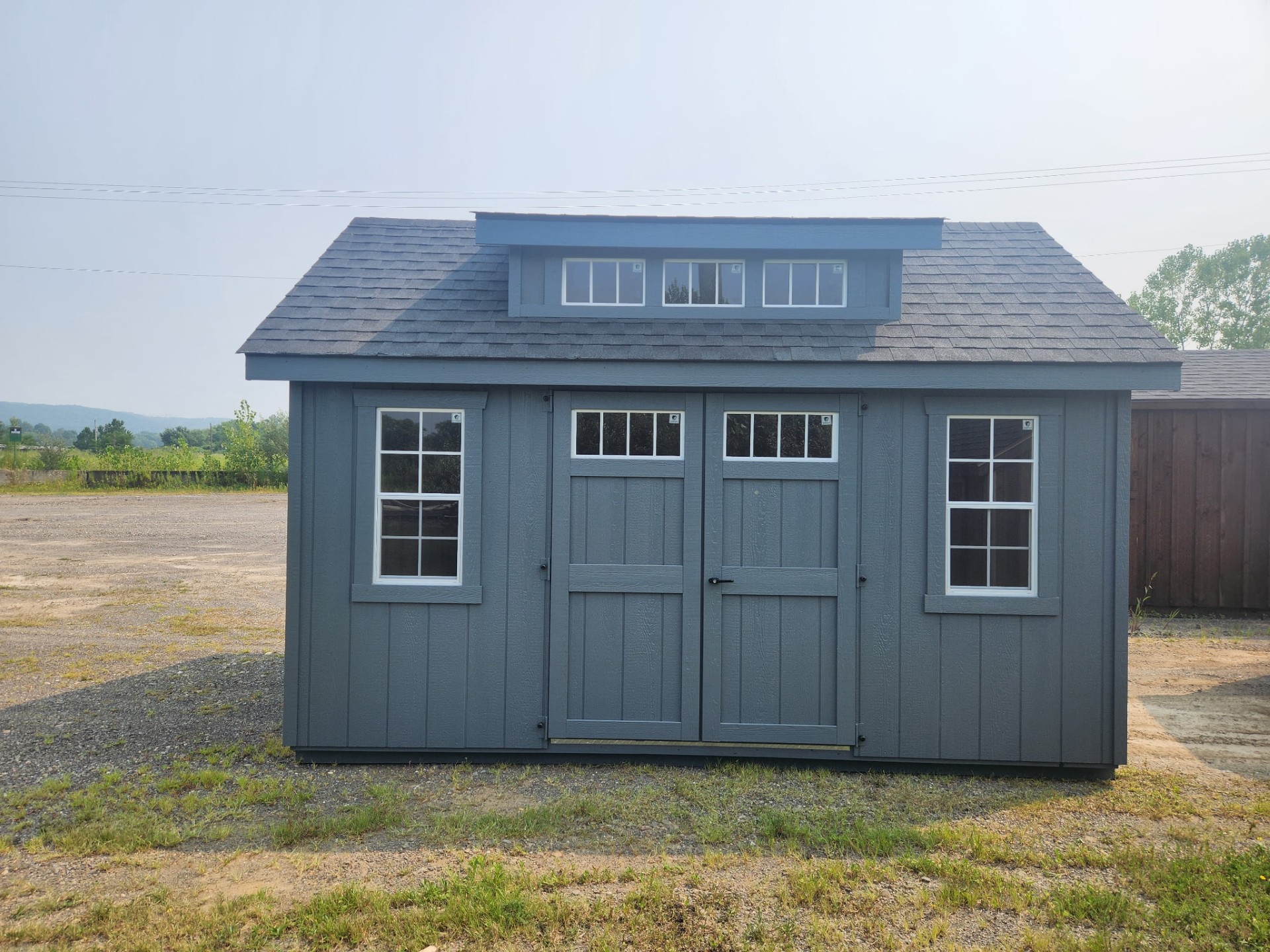 Shed with transom dormer on roof, double doors below and windows on either side of double doors