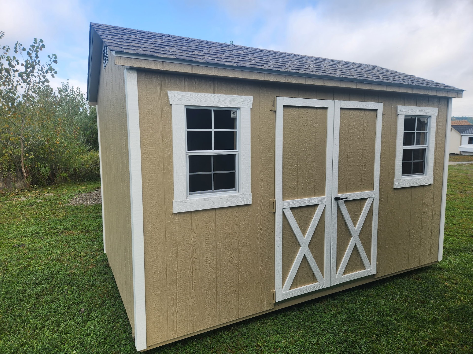 Tan a frame style shed with double doors and two windows on front with shingled roof