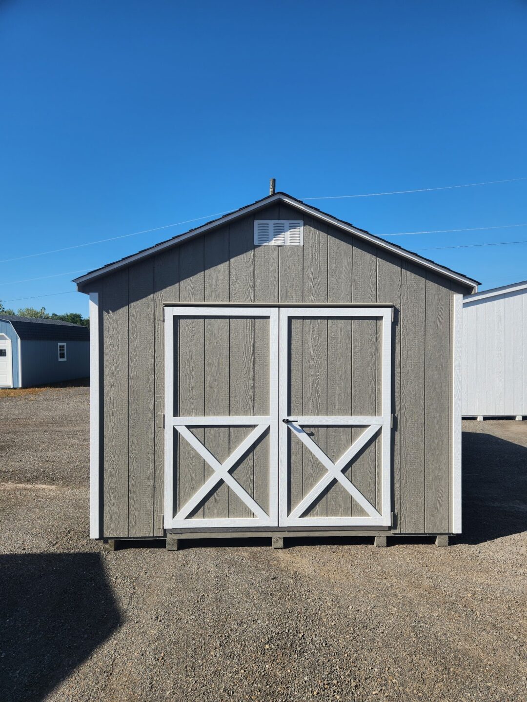 A Frame shed with clay siding, white trim, double doors, gable vents and shingled roof