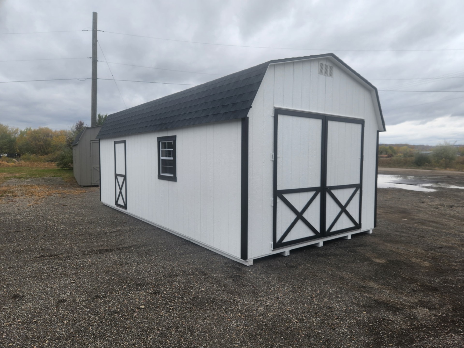 White barn with black trim and large double doors with a small side door and window